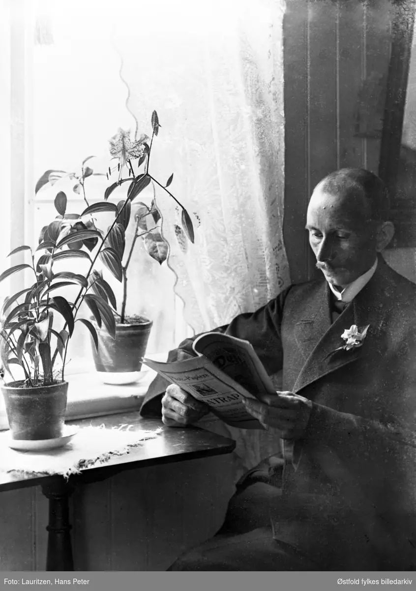 Selvportrett av en lesende fotografHans Peter Lauritzen foran vindu med potteplanter.
Tidskriftet han leser i er et tysk fotografitidskrift. Han hadde lært seg nok tysk til å kunne bestille fotoutstyr direkte fra Tyskland, så alt hans utstyr ble derfor importert derfra.