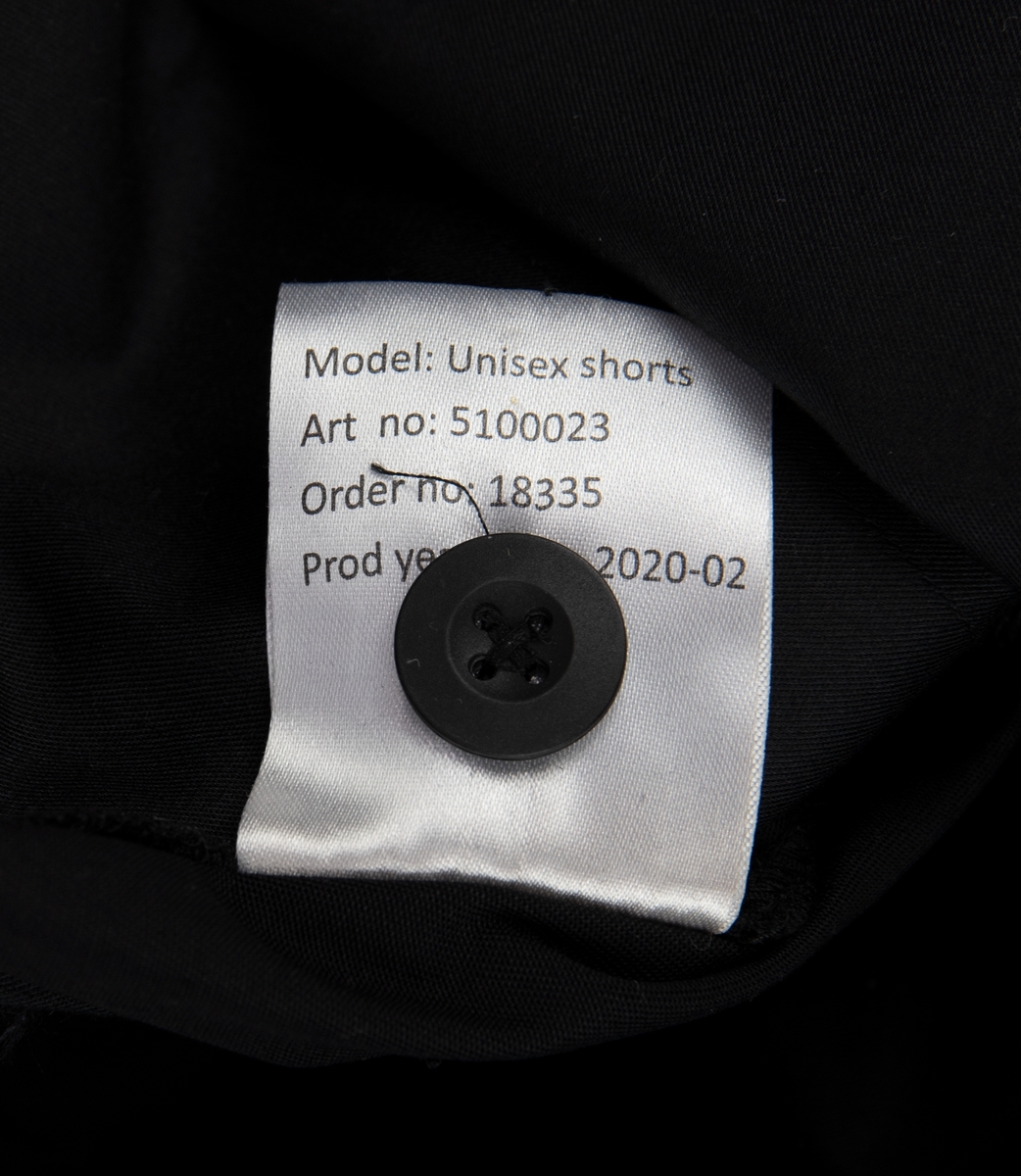 Svarta kortbyxor av 65% polyester och 35% bomull. Två snedställda fickor fram, två sidofickor och två bakfickor. En metallring fäst i linning för nycklar på höger framsida. Linning med hällor för bälte. Märke med SJ:s logotyp över höger bakficka. Gylf med metalldragkedja och plastknapp. 
Tyglapp på insidan där det står "SJ UNIFORM 52" samt en tyglapp med produktinformation, tvättråd och en extra plastknapp.