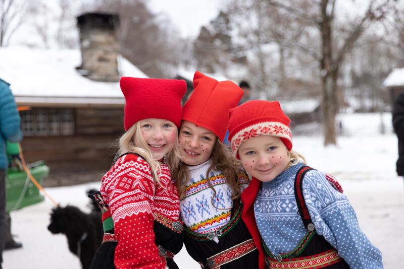 Bildet viser tre smilende jenter med nisseluer og strikkegensere som ser inn i kameraet (Foto/Photo)