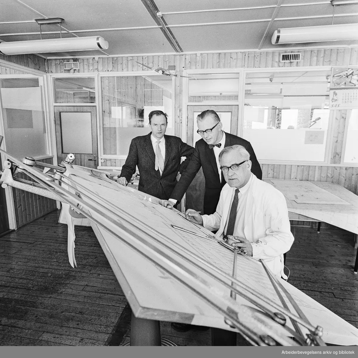 Arkitekt Odd Nansen (foran), sivilingeniør Kristoffer Borgsti og arkitekt Kåre Bratsberg arbeider døgnet rundt for å bli ferdig med den nye ekspedisjonsbygningen på Oslo Lufthavn Fornebu. Mars 1962.