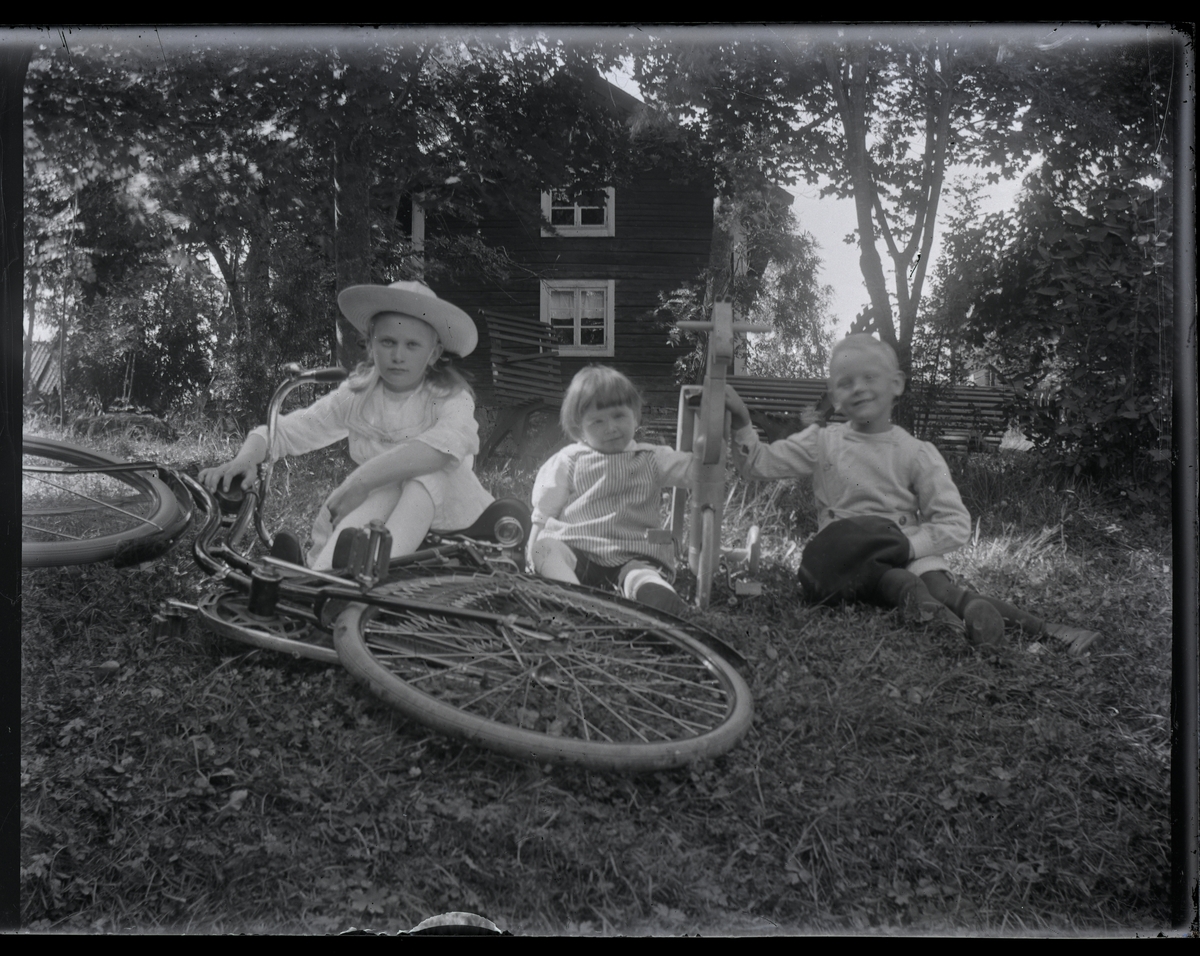 Grupporträtt, tre barn och en cykel.