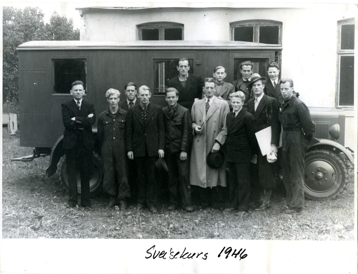 Sort-hvitt bilde av gruppe med menn foran gammeldags buss (Foto/Photo)