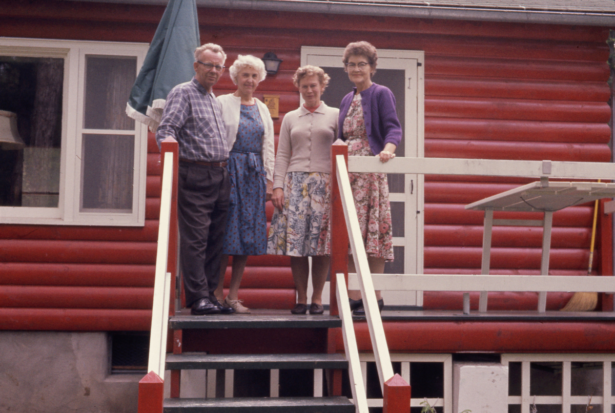 Rød hytte tre kvinner og en mann
