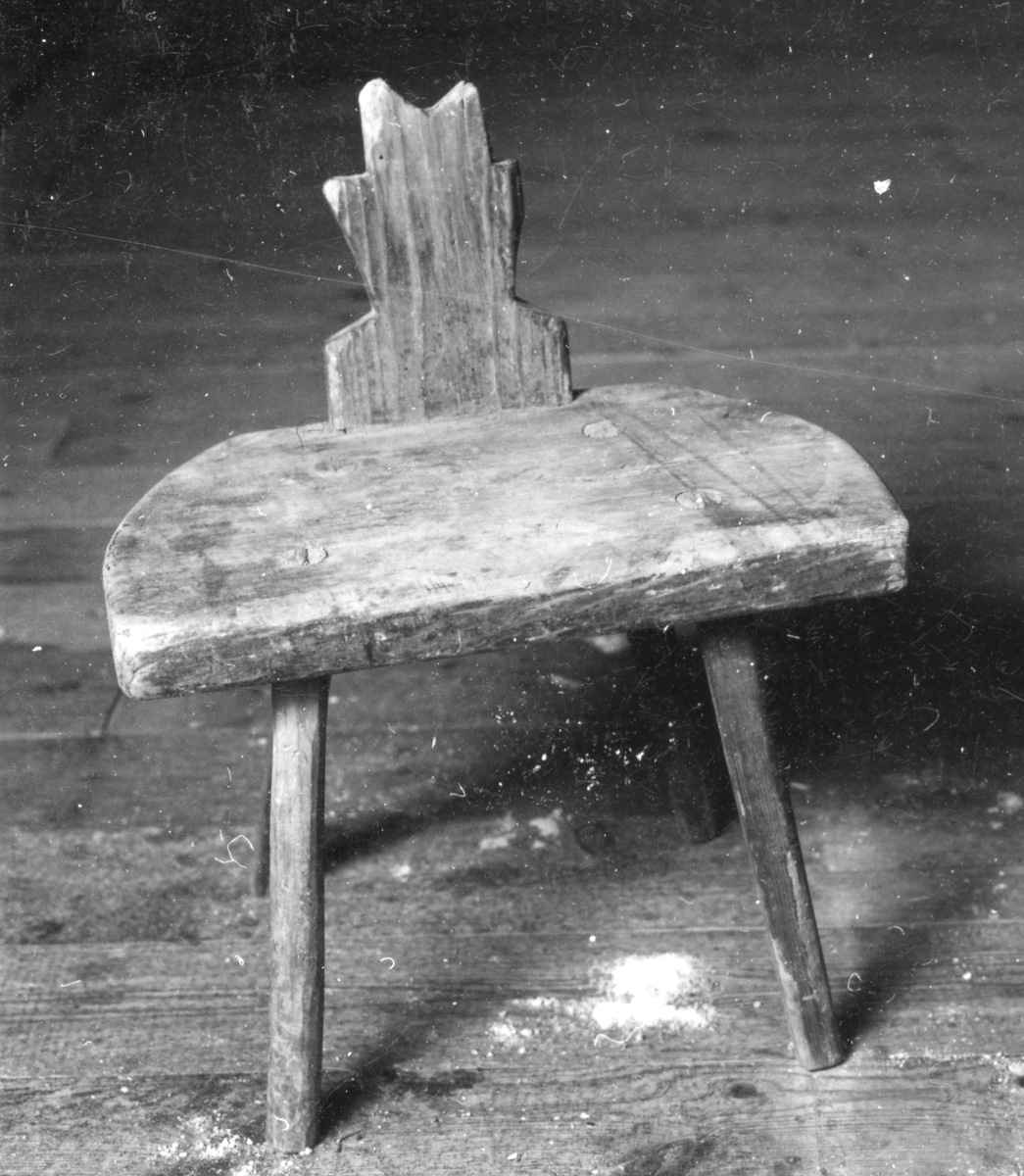 Barnstol med spår av brun målning, halvcirkelformad sits med infälld ryggbricka. 4 st runda något utställda ben intappade i sittsen.