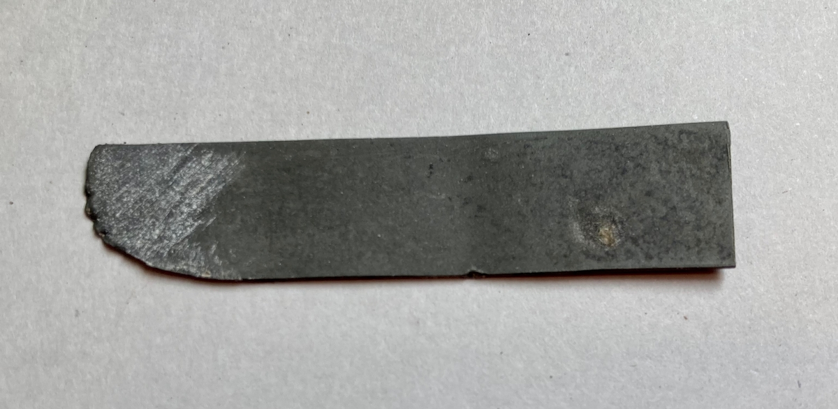 En liten metllbit delvis formet til et knivblad.