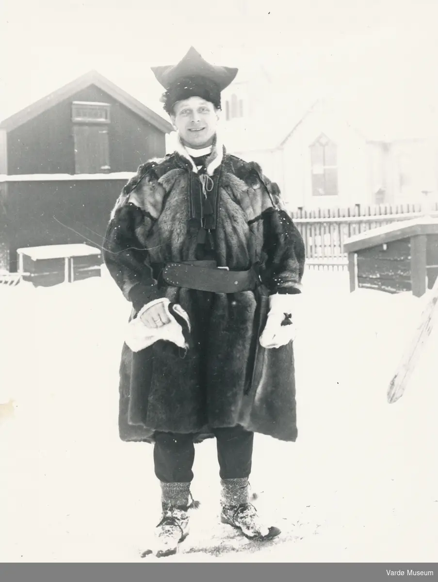 Johan Oskar Grasmo utenfor prestegården, ikledd samisk pesk og herrelue. Ca. 1910-1920