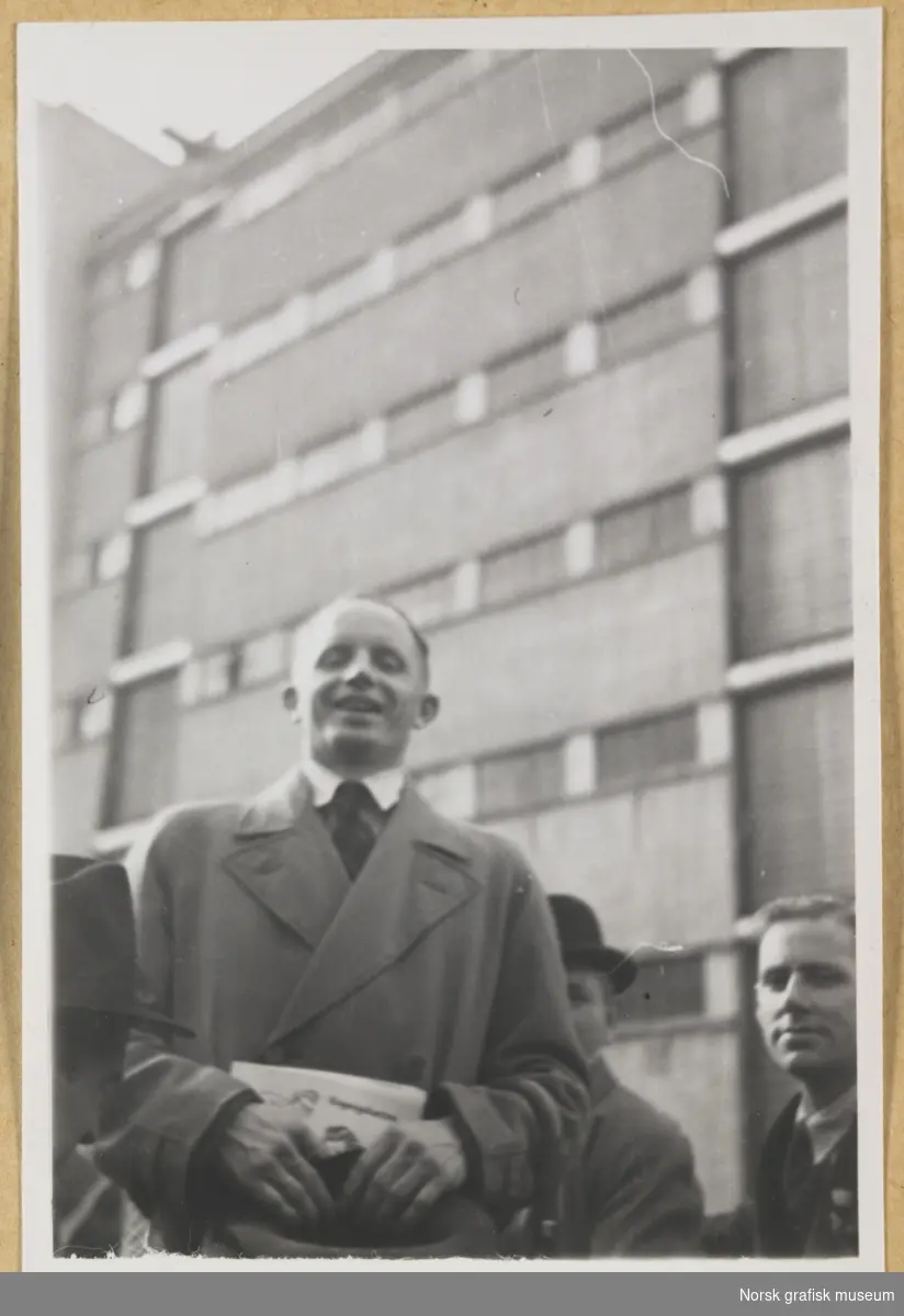 Utendørsmotiv. To menn foran en stor bygning. Fotografert i forbindelse med Vestlandsk Trykkerstevne i Bergen, 1946.