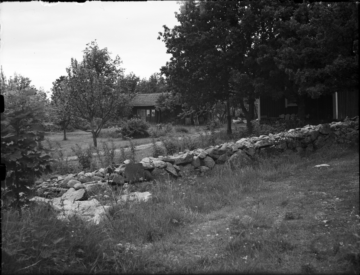 Litet hus med trädgård och en stenmur i förgrunden, Uppland