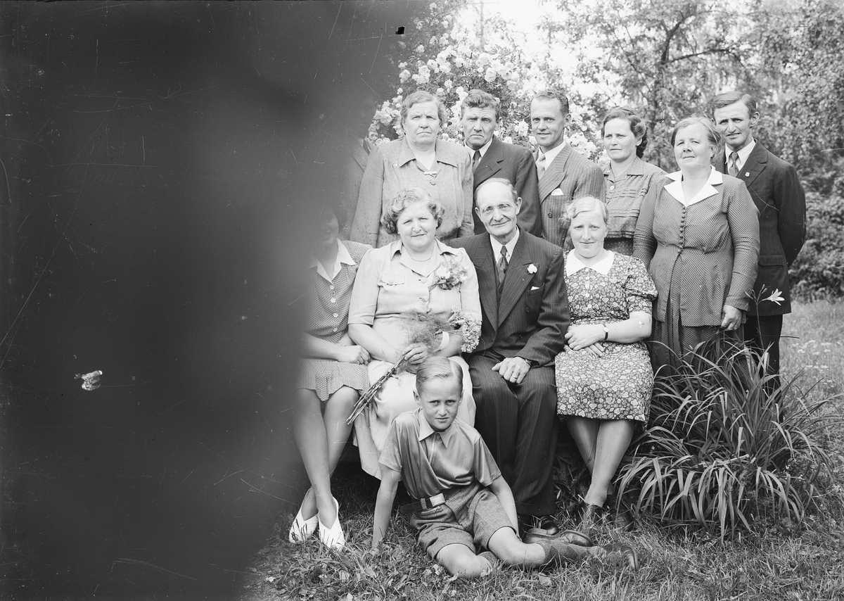 Järnsvarvare Gustaf Carlsson med familj samlad i trädgården, Östhammar, Uppland