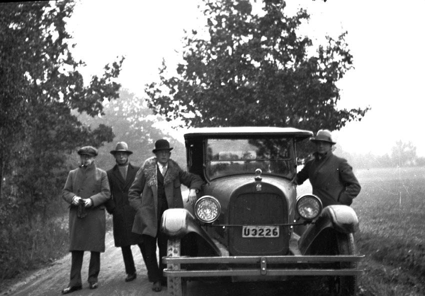 Fyra män utanför en bil.