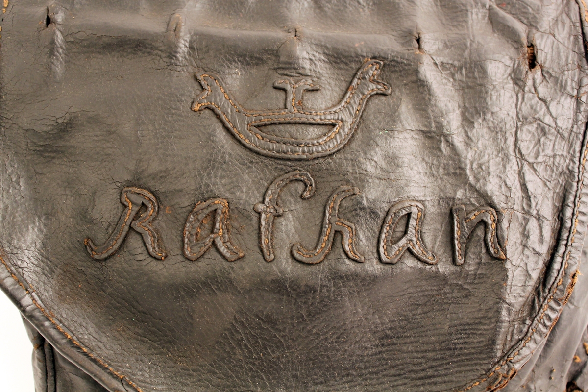 Lösväska, saknar bärrem. Klaffen är med sydda bokstäver i
läder: "Rathan" under krona. Under klaffen finns märken efter
låsanordning.