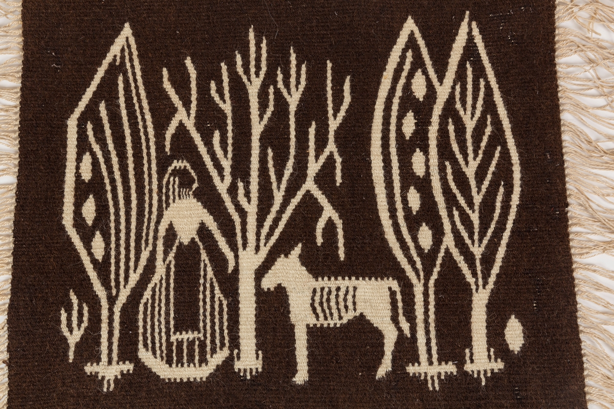 Billedvev i ull. Motiv som trolig forestiller en dame og en esel i en skog. Håndarbeid, vev. Opphengskant av tre.
