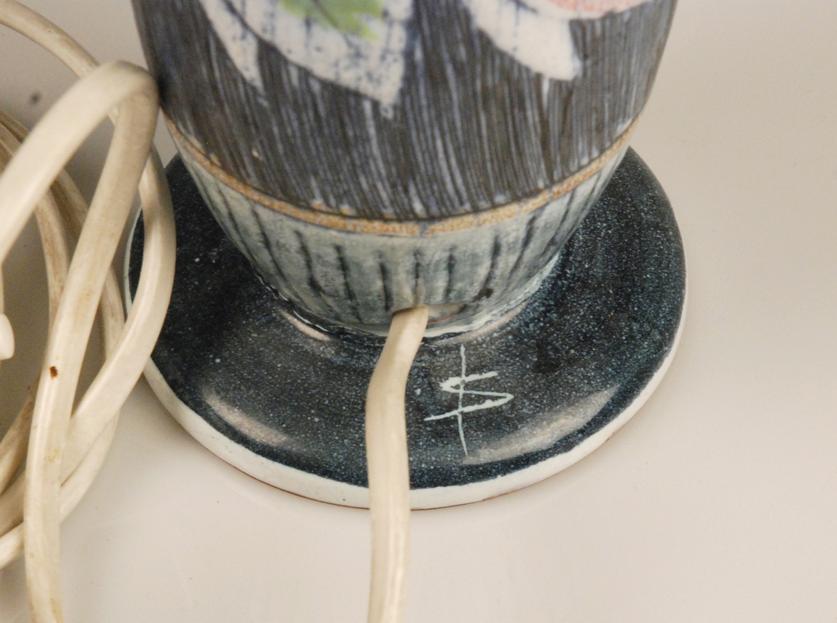 Lampfot i blå sgraffito-teknik och blomdekor i grönt och rosa. Glaserad. 

Tillverkare är Tilgmans Keramik i Göteborg, ett företag som var en viktig inspirationskälla för Alingsås Keramik under 1950-talet. 

Stämplar under: 
Tilgmans Keramik
Made in Sweden