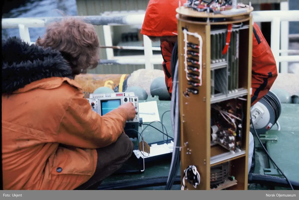 To menn arbeider med elektronikken til ROV'en "Snurre" på et skipsdekk.