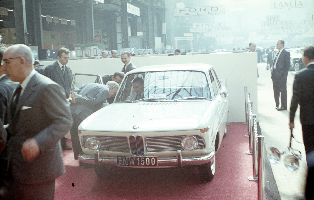 Foto fra en bilmesse i Frankrike. En BMW granskes av interesserte menn i dress.