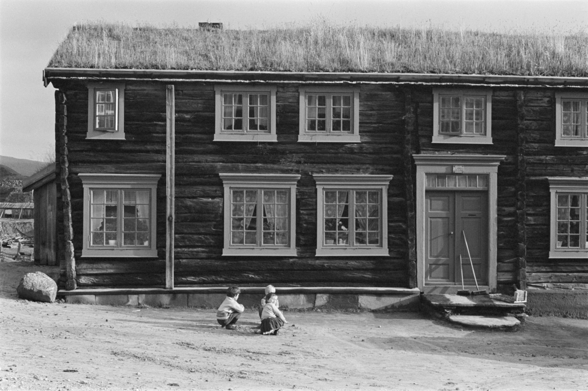 Barn leker foran et laftet tømmerhus på Røros.