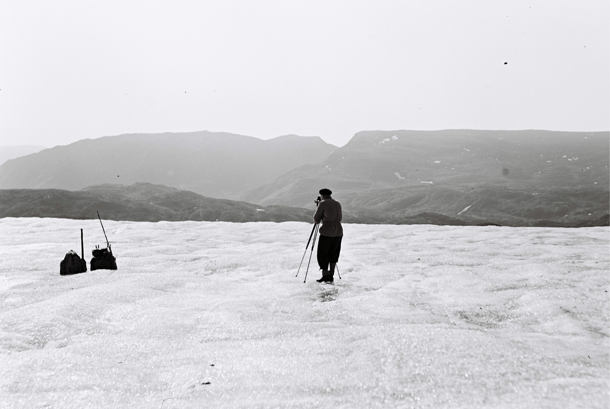 En mann står og filmer på Finnmarksvidda. Fotografert ca. 1953.