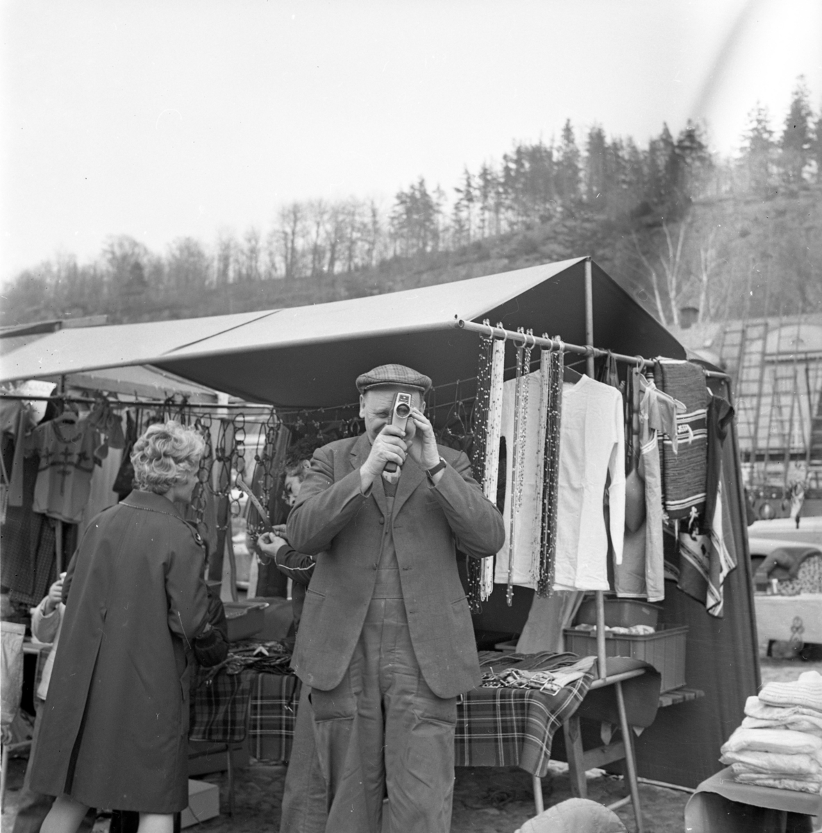 En man med keps och filmkamera står vid ett marknadstält, vänd mot och filmar fotografen. Mannen är Torsten "Bohultarn" Karlsson.