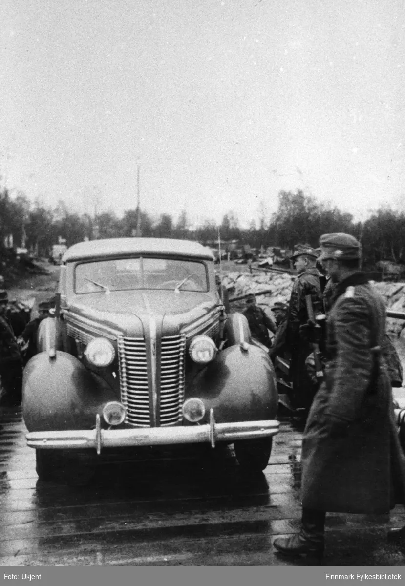 Tyske soldater tar fergen over ved Utnes i Svanvik. Bilen er Buick Convertible Sedan 1938-modell uten registreringsnummer. Bildet er tatt i samme situasjonen som GK-FV.0001222.  

