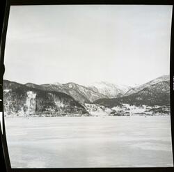 Fotografi av en fjord som er frosset til is som det går noen