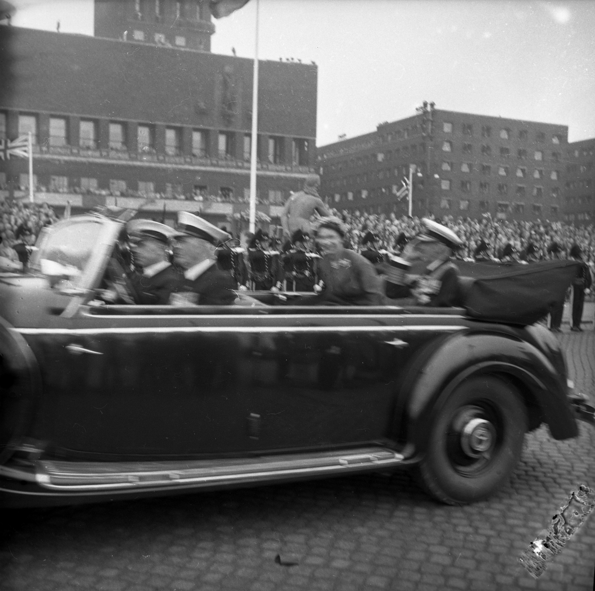 Dronning Elizabeth II på statsbesøk i Norge. Dronningen og Kong Haakon på vei i åpen bil til omvisning i Oslo Rådhus. Publikum langs ruten.
