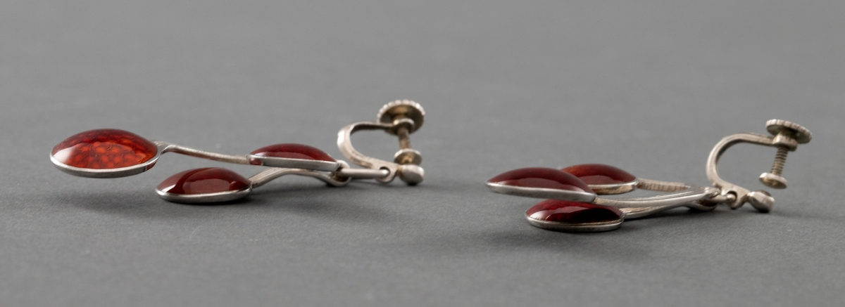 To kirsebærformede øresmykker i sterling sølv med rød speilemalje. Hvert smykke er formet som tre kirsebær som knyttes sammen i roten på stilken.