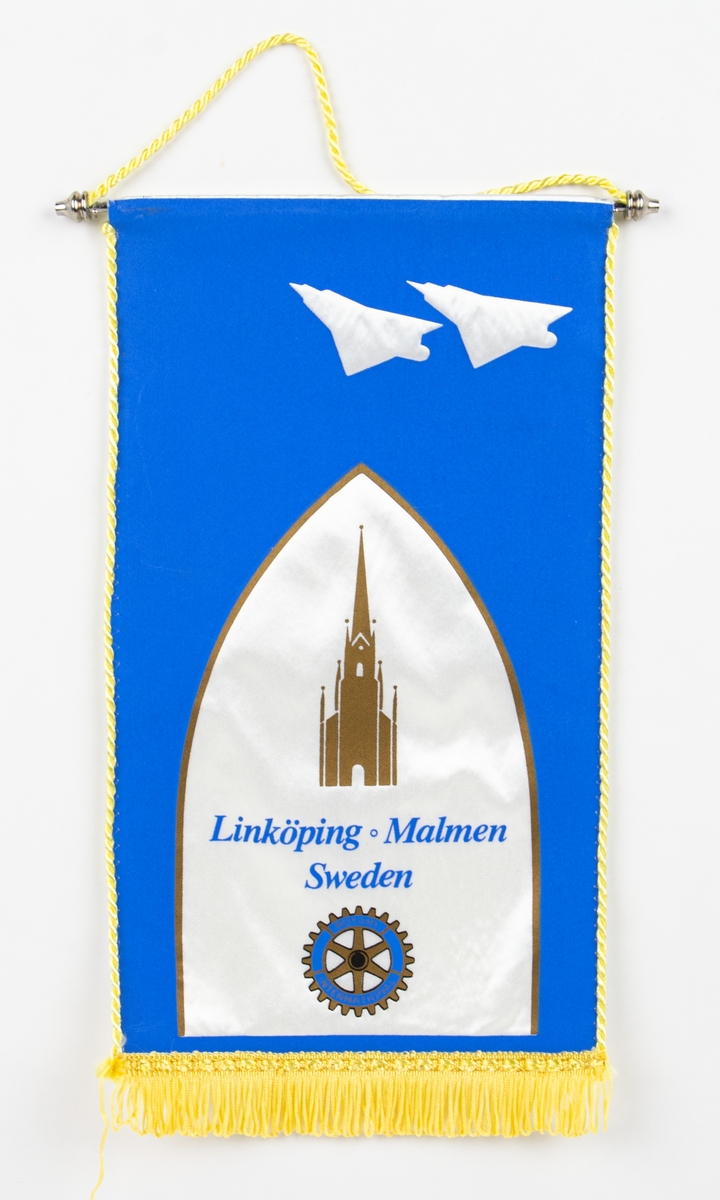 Standarflagga för: "Linköping o Malmen, Sweden. På flaggan syns två Viggenplan, Linköpings domkyrka och ett kugghjul med texten: ROTORY INTERNATIONAL.