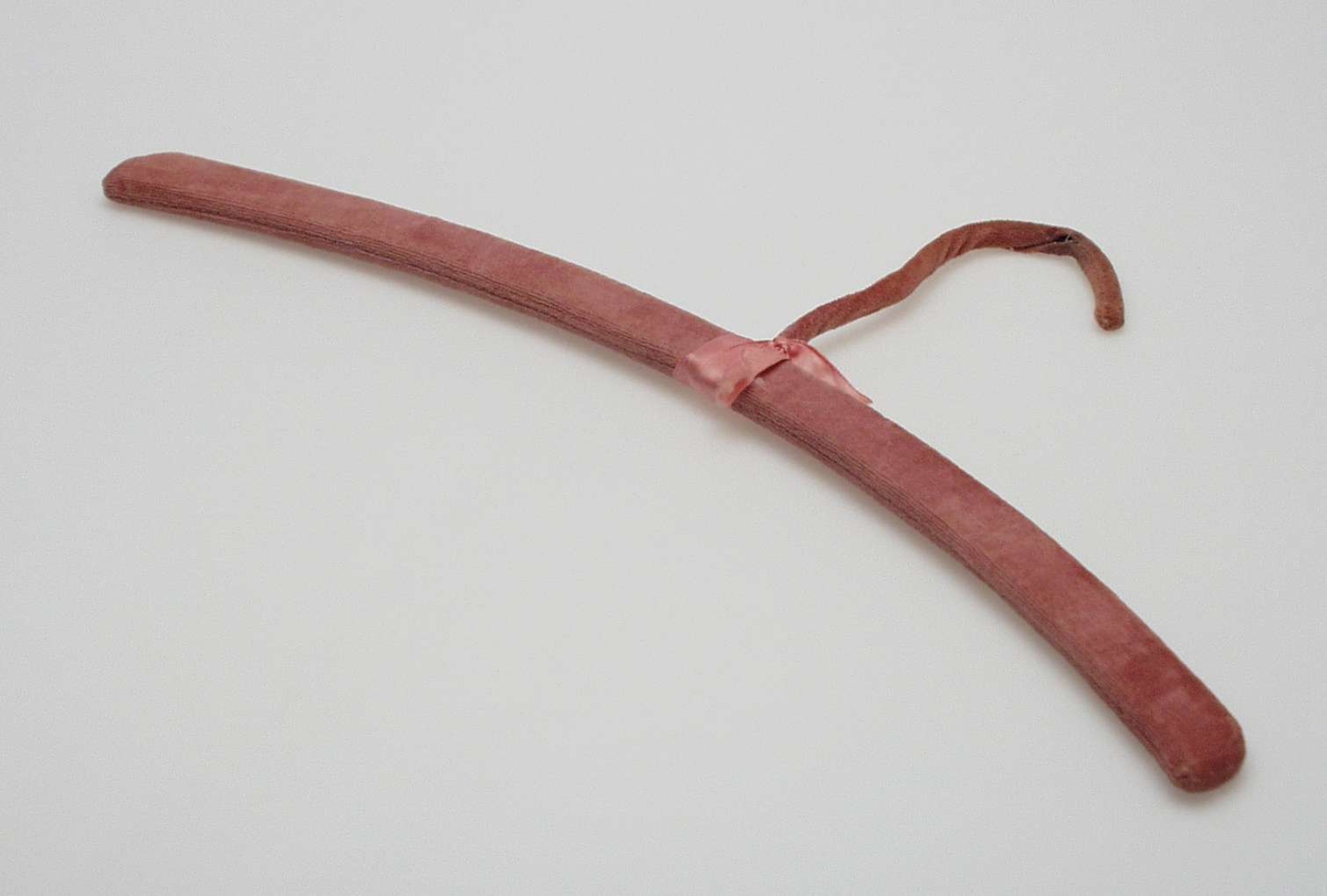 Trekk av gammerosa fløyel, maskinsydd, er trukket på fra hver side, stiftet på med stiftemaskin. Rosa satengbånd, 1,5 cm bredt er viklet om skjøten og knyttet med sløyfe. Metallkroken er trukket med fløyel.