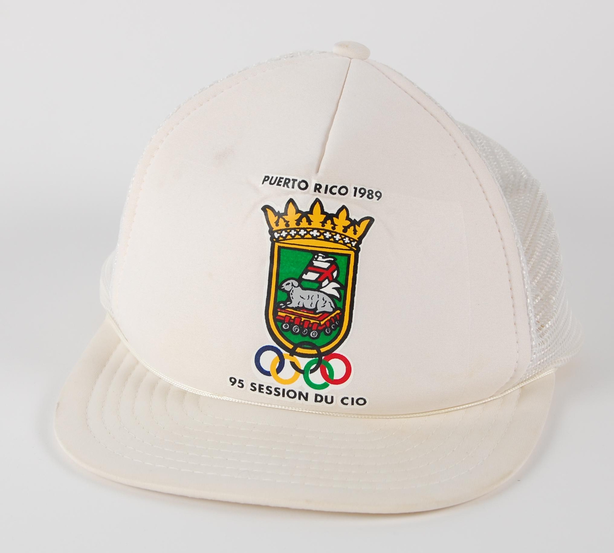 Hvit skyggelue med logo fr arrangementet "95 SESSION DU CIO" i Puerto Rico i 1989. Lua har strammespenne av plast.