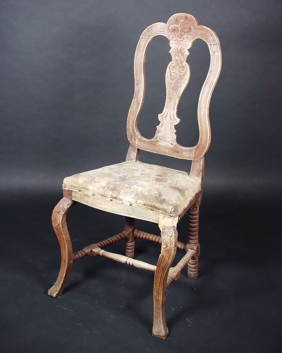 Stolen er av bjørk med stoppet sete av lær. Stolen har utskjæringer i rygg og på bein. Sprossene er dreide.