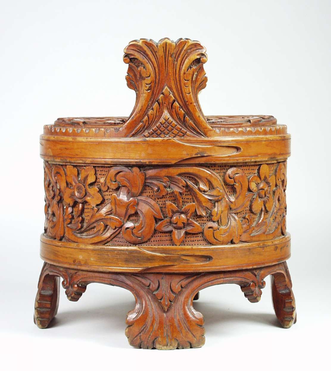 Ambaren er lagget av åtte staver. Fire staver er forlenget til bein og to til ører. Beina og ørene skrår utover. To flate gjorder. Lokket er laget av ett stykke påsatt håndtak. Beina og ørene er dekorert med akantuspalmetter. Rundt ambaren går en akantusranke i forholdsvis høyt relieff på prikket bunn. I hver buktning på ranken er det satt inn fire-, fem- eller seksbladete blomster. En sett fra siden og resten ovenfra. Ranken har kraftig smetting av bladene fra sideskuddene. Ambaren er lakket. Lokket har tilsvarende akantusskurd som ambaren, med fire fembladete blomster. På lokket har også noen av bladene lansettform med tagger.Håndtaket har gjennombrutt akantusskurd i rundskurd. Enkel låsepinne.
Ambaren er tidligere katalogisert som laget av einetre.