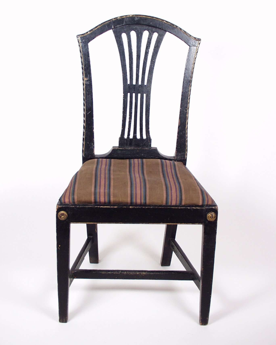 Stolen er av furu, malt svart med enkel gulldekor. Setet er løst, med stripet trekk i brunt, rosa og blått.