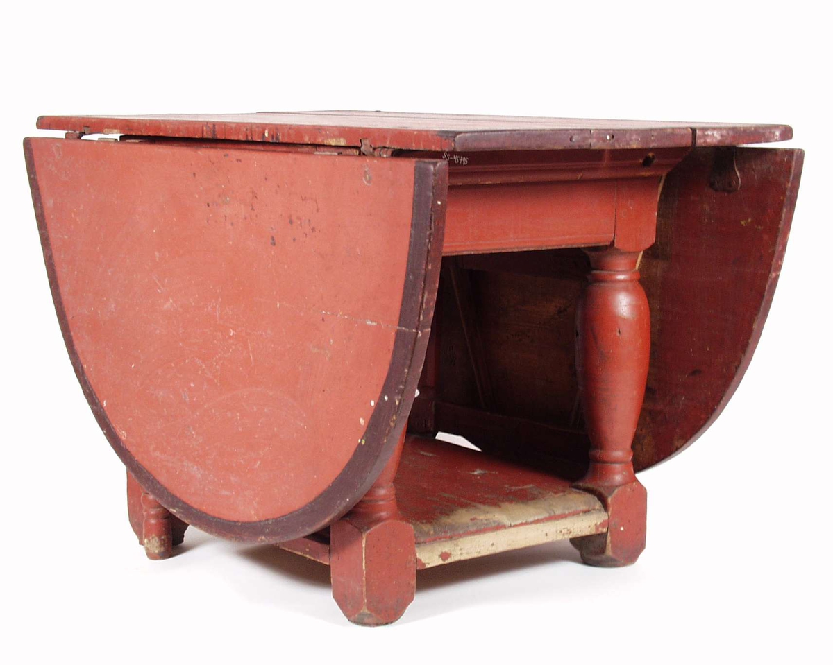 Et klaffebord i furu som er blitt malt rød med smal svart kant på bordplaten.
Bordet har fire dreide ben og en underplate som binder klaffebordet sammen.
Hver side av bordet er det grinder som holder klaffene oppe.
