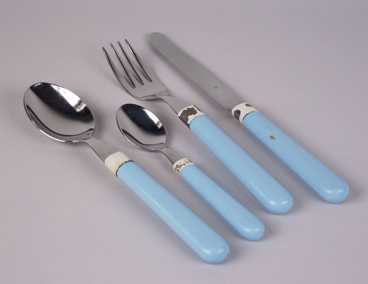 Bestikk i stål med seks gafler, seks kniver, seks skjeer  og fem teskjeer. Skaftet er i lyseblå plast. Sølvfarget belegg er delvis skallet av.