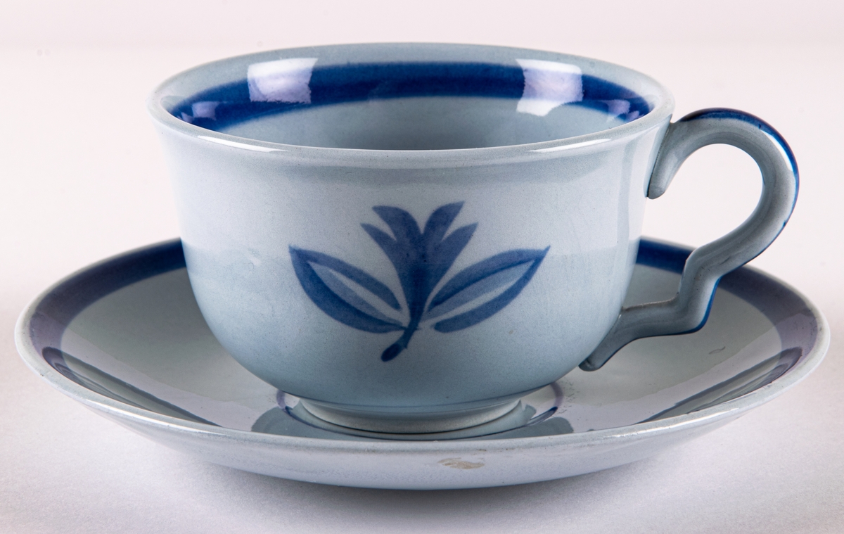 Kaffegods i flintgods, dekor Blått band av Arthur Percy, skapad 1931. Handmålad blå bladrosett samt blå rand på fatets kant respektive koppens insida.