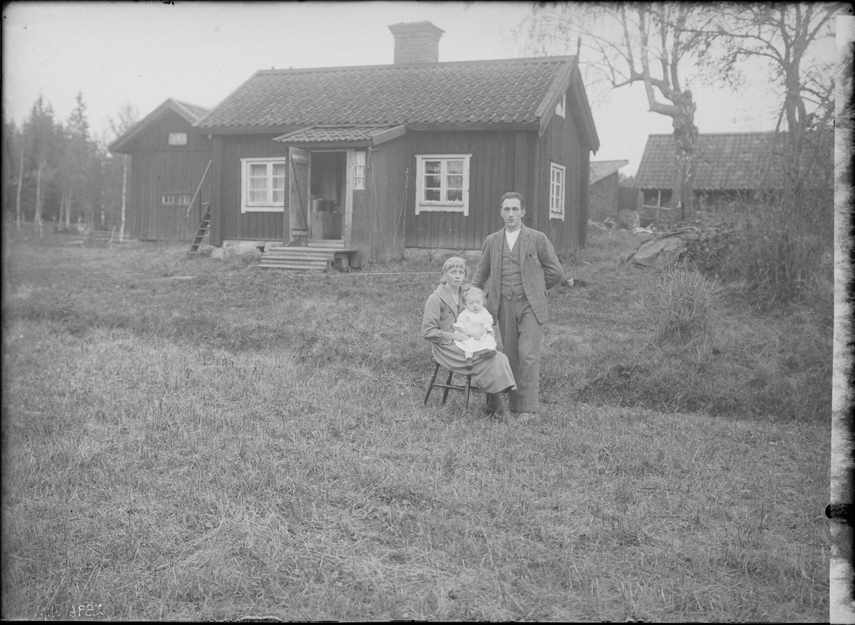 Fotografering beställd av Sven Lundström. Föreställer sannolikt skogsarbetaren Ivar Herbert Lundström (1899-1967) med hans hustru Alma Kristina Johansson (1896-1978) och dottern Margit Birgitta (1923-2000). Här bosatta på Svedjorna under Hälljö i Fläckebo.
