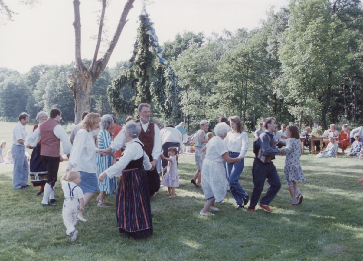 Dans kring midsommarstången vid Långåker 1:3 Hembygdsgården 1993. I mitten ses folkdräktsklädde Berny Gustafsson.
Relaterade motiv: A03389 - A03408.