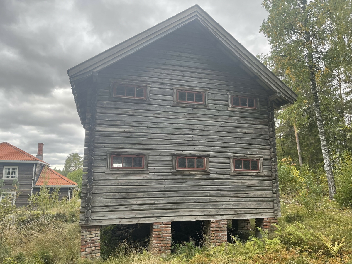 På noen steinskjær nord for funksjonærboligen Skjærdal på Klevfos papir- & cellulosefabrik står en stabburliknende laftebygning som har fungert som uthus og lager for de familiene som har bodd i den nevnte funksjonærboligen.  Skjærdal ble bygd i 1919-1920, og det er grunn til å tro at dette uthuset må være reist like etterpå. 

Det dreier seg om et laftet hus med rektangulært grunnplan på 6 X 6 meter.  Huset er oppført i to etasjer på 14 teglsteinsilarer i tosteins forband (ca. 50 X 50 centimeter i tverrsnitt).  Høyden på disse pilarene varierer fra 45 til 105 centimeter, fordi terrenget huset er reist i er ujevnt.  Det er for øvrig tydelig at byggegrunnen har skapt visse problemer i den forstand at det har oppstått setninger der hvor muringa ikke er utført direkte på berg.  Fem av dem later av den grunn til å ha vært demontert og deretter gjenoppmurt på såler av betong.  Et par av dem som ikke er restaurerte preges av utfellinger som antakelig skyldes fuktproblematikk i marksjiktet. En pilar er også noe vridd i forhold til det som antas å ha vært opprinnelig stilling.  På to av pilarene under husets midtparti ligger kviler det en kraftig bjelke (14 X 16 centimeter i tverrsnitt) som støtter de seks golvlunnene, som har et tverrsnitt på 13 X 15 centimeter. 
Foran bygningen på gavlen er det ei trapp med to trinn opp mot et repos, lagd av 1-toms impregnerte bord i nyere tid, antakelig samtidig med at noen av pilarene under bygningen ble utstyrt med betongsåler. 

Laftebygningen later til å være oppført av grantømmer.  Den har ei labankdør på søndre gavlvegg. Døra er kledd med bord, lagt i plogmønster.  Gjennom denne døra kommer man inn i en to meter bred gang mot en bordvegg med tre dører.  Bak disse dørene er det tre buer, atskilt av lettvegger med paneler av pløyde bord (8, 5 X 2 centimeter).  Dørene inn til buene er vanlige, enkle labankdører.  I gangen i 1. etasje finnes også ei trapp med vanger av 18, 5 X 5 centimeters plank og trinn av 3, 3 centimeter tjukke golvbord.  2. etasje framstår nå som et åpent rom, med unntak av rekkverket som skjermer trappeløpet ned til gangen i 1. etasje fra tre sider.  Spor i golvet tyder imidlertid på at også 2. etasje har hatt samme planløsning som 1. etasje, med tre buer med bordvegger mellom.  Den øvre delen av gavlveggen mot sør er forsterket med to vertikale labanker, lagd av planker (13, 5 X 6, 2 centimeter), festet med gjennomgående, gjengete bolter. På gavlveggene er det rektangulære vinduer.  Vindusgrindene (93 X 39 centimeter) er nye, men omrammingene er originale, og grindene er antakelig kopier av de opprinnelige.  Med unntak av de to vinduene på sørveggen i 2. etasje er alle vindusåpninger utstyrt med smijernsgitter på innsida, antakelig for å forebygge innbrudd. 
Den stabburliknende uthusbygningen har sperretak med seks sperrepar, hvorav de ytterste er montert helt inntil de tømrete røstene.  Taket har bordtro, lagt som under- og overliggere i takflatenes fallretninger.  Dette undertaket er lektet og tekket med krumtegl. 

På registreringstidspunktet oppbevarte museet utrangerte kjøkken- og kontorinnredninger i et par av buene i husets førsteetasje.  
