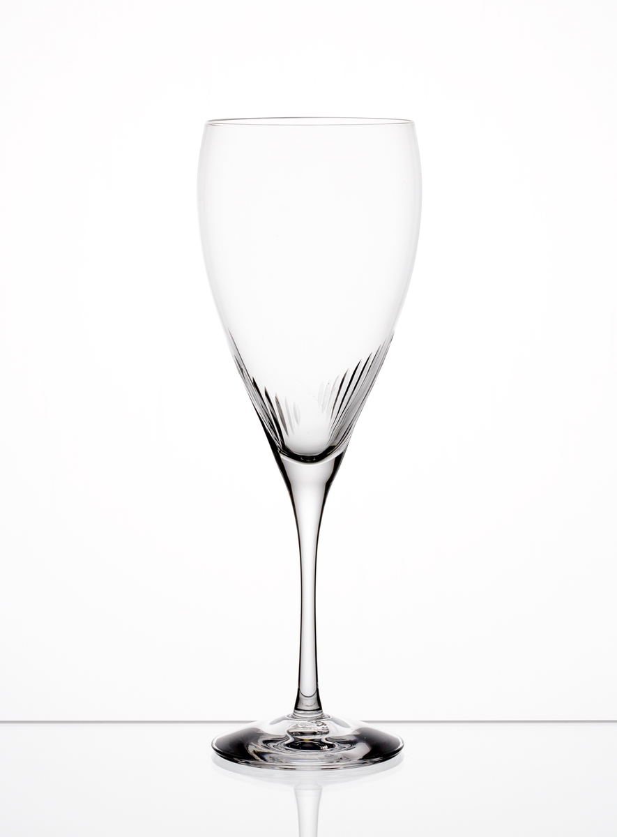 Formgiven av Erika Lagerbielke. Ölglas med nio plus nio stående skär placerade där skålen övergår i ben. Genomskinlig etikett med orre och text i silver.
