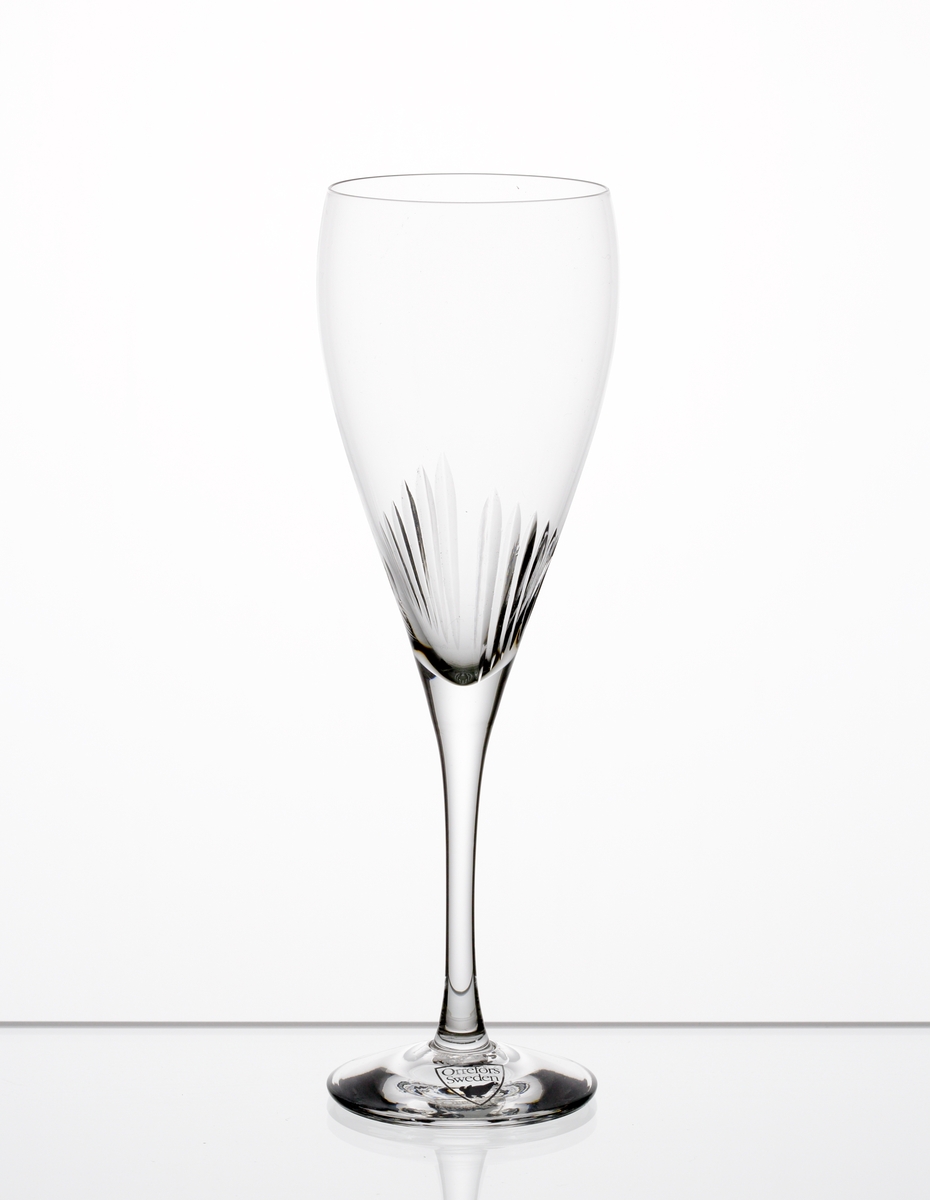 Formgiven av Erika Lagerbielke. Ölglas med åtta plus åtta stående skär placerade där skålen övergår i ben. Genomskinlig etikett med orre och text i silver.