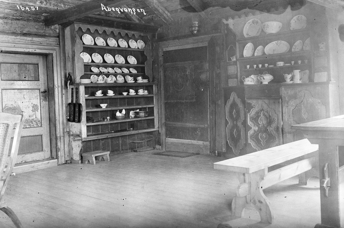 Interiør med hyller, skap, servise, serveringsfat, serveringsskåler, benk og dører med ornamenter i et bygg på Auenvangen, Gol, 1914.