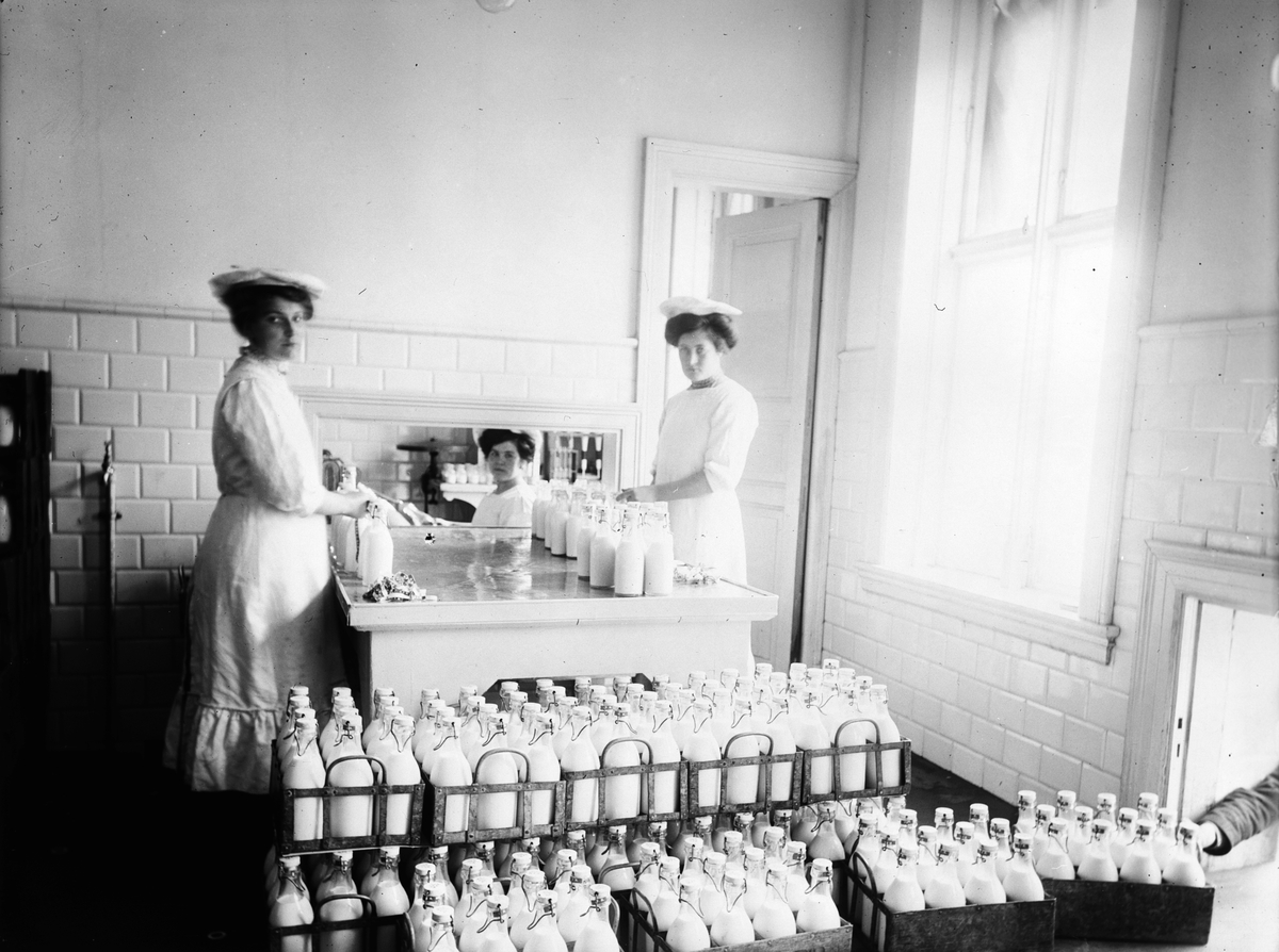 To kvinner fyller melkeflasker for De Forenede Meierier. Fotografert 1911.