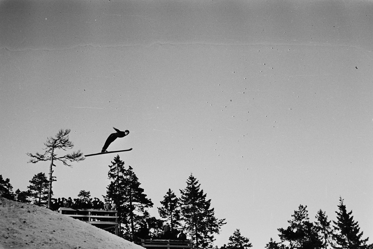 Skihopper i lufta i Holmenkollbakken, Oslo. Fotografert 1940.