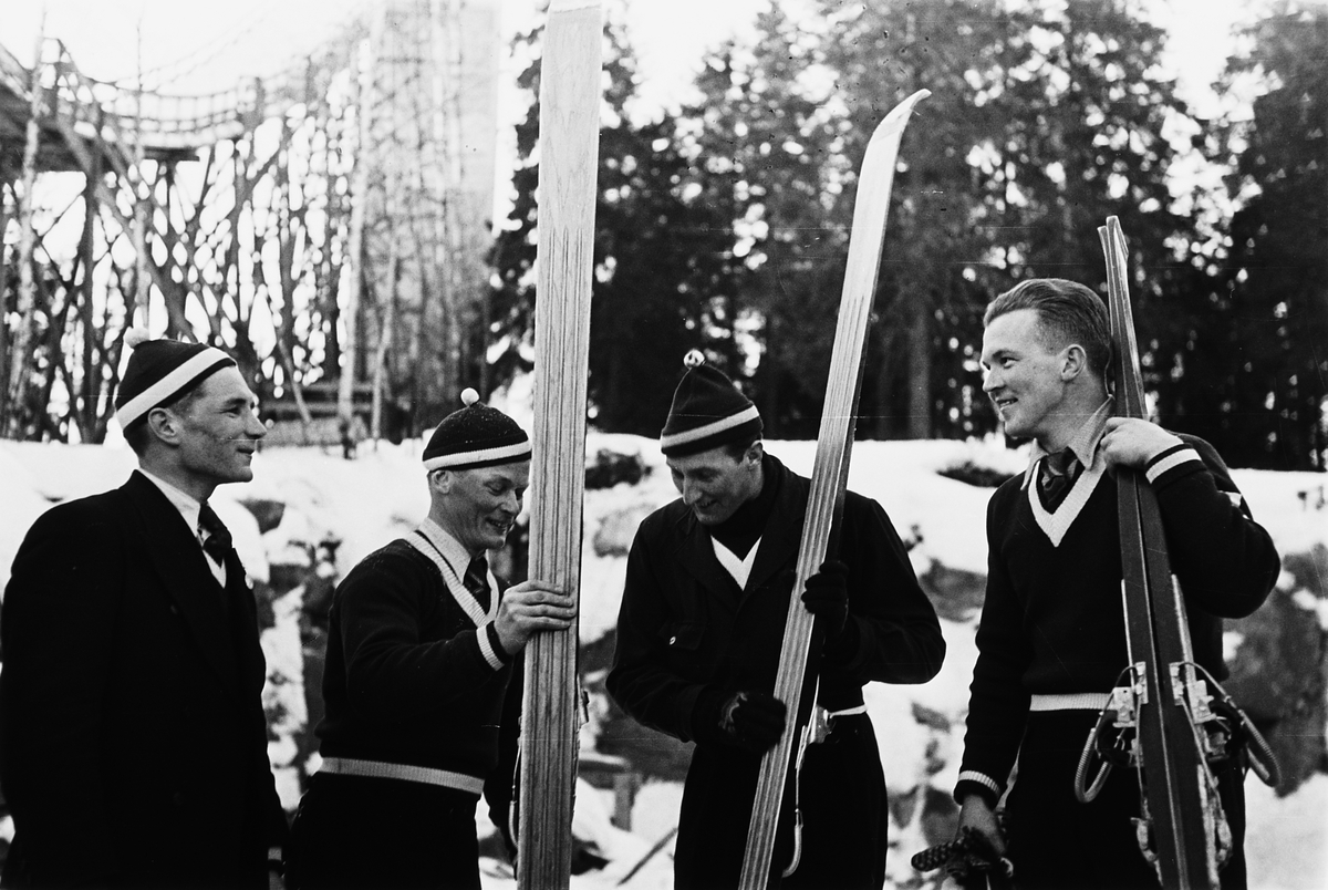 En gruppe hoppere i fullt skiutstyr, topplue, genser og siste utgave av hoppski. Antatt Torbjørn Falkanger til høyre. Fotografert 1940.