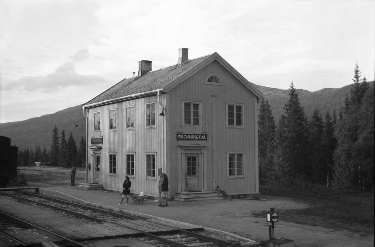 Svenningdal jernbanestasjon i Nordland.  Fire personer pluss barn i barnevogn venter på toget.