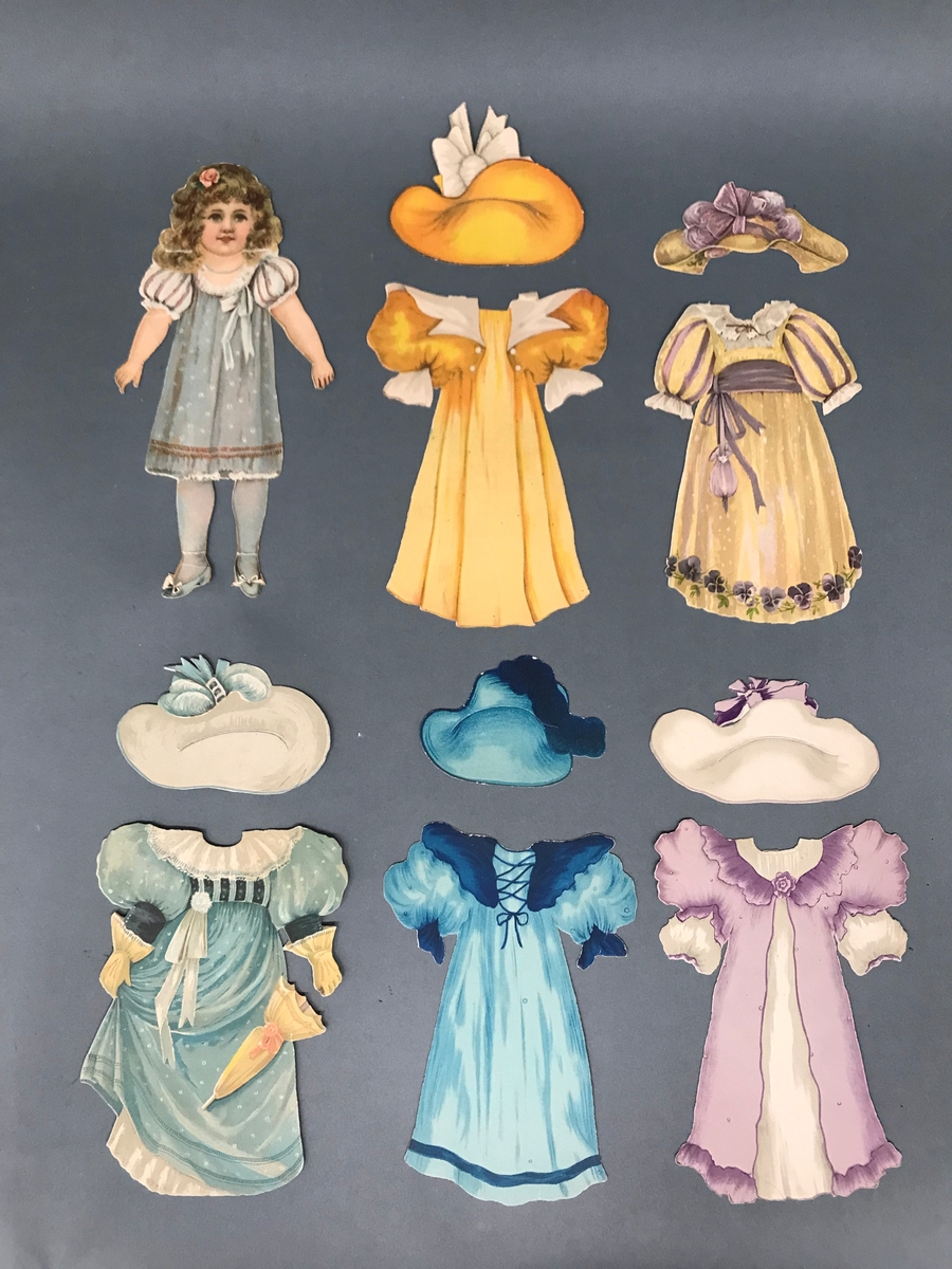 Papirdukke med fem kjoler og tilhørende hatter