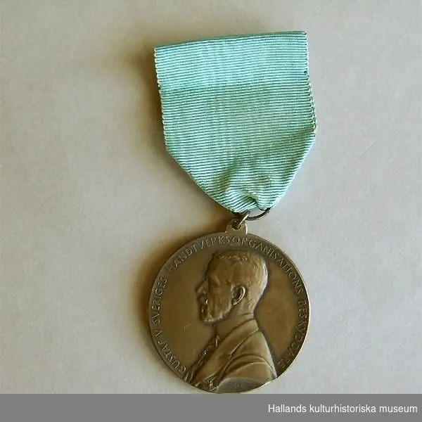 Rund medalj, försilvrad. Diameter 4 cm. Medaljen är fastsatt i ett blått sidenband. Framsida: Gustav V i profil samt text: "GUSTAV V SVERIGES HANTVERKSORGANISATIONS BESKYDDARE". Baksida: Kvinna knytande en krans, sittande på en tron. En sköld med tre kronor samt text: "TILL YRKENAS FÖRKOFRAN OSCAR DAHLBERG 1939". En säkerhetsnål fastsydd på sidenbandets baksida.