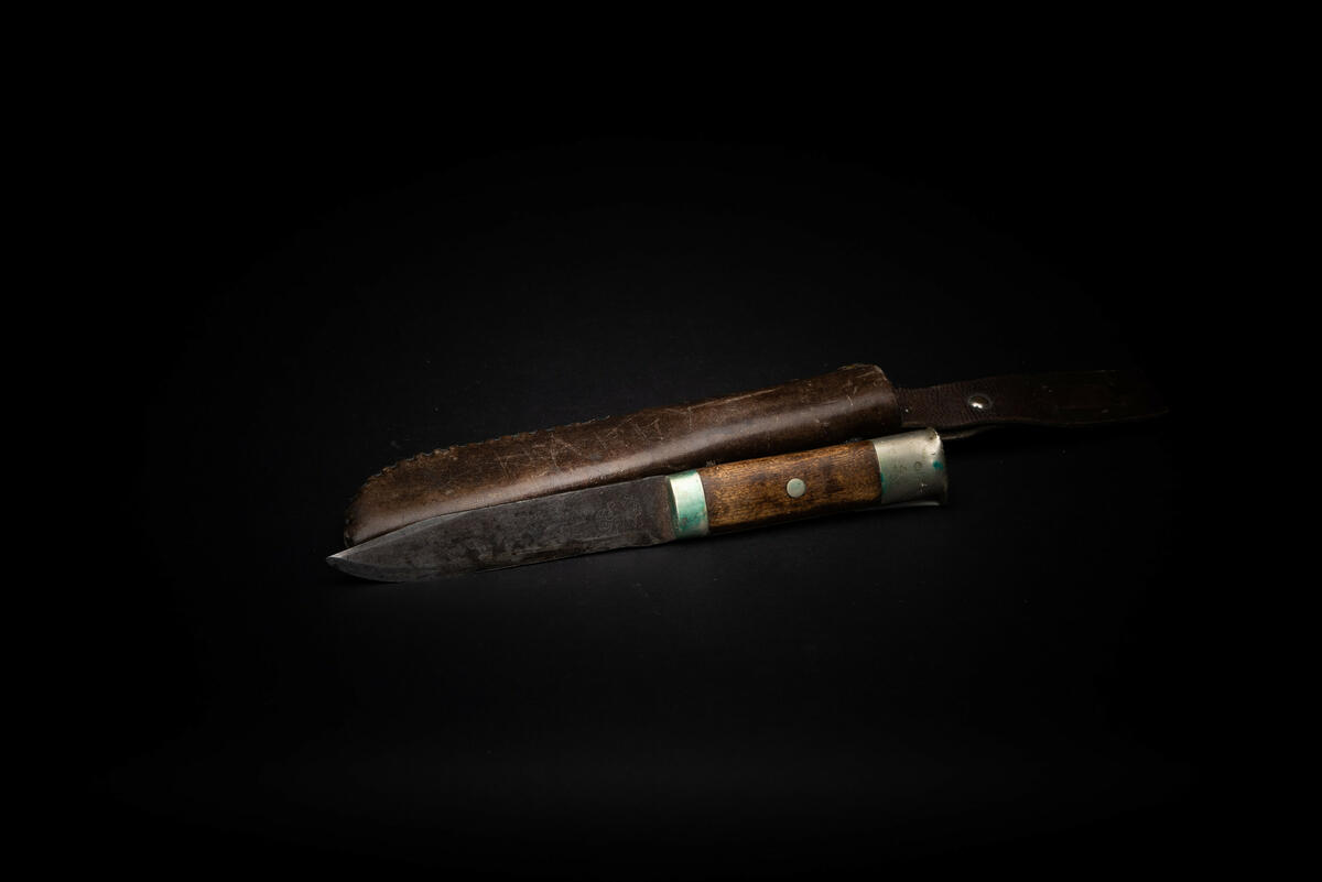 Slirekniv i stål, treskjefte og nysølv holk (endestykket), som er formet slik at den kan brukes til å skrape i skiranden. Slire i kromgarvet brunt lær, håndsydd med nysølvtråd, med regulerbar patentert bærestropp. Det står "slirkniv" på sliren. Dette kan bety at den er produsert i 1933, i overgangen fra Slirkniv til Sliring. En annen forklaring er at sliren er byttet fra en annen kniv. 

Denne gjenstanden har motstridende kjennetegn. Den mangler stempel av kronet K i bladet, noe som gjør at den ikke er produsert på Kongsberg, men i Mora fra 1957 til 66 (medmindre K-en er slitt bort). Andre modeller produsert på Kongsberg har innskrift MADE IN NORWAY i bladet, mens denne har OSLO – NORWAY, noe som også peker i retning Mora. Men at sliren er av eldre utgave, av typen "Slirkniv" kan bety at det er en Kongsberg-kniv (1933-56). 

Fra katalogen, juni 1934: 

Bergans patenterte Sliring. Stor modell - 23 1/2 cm. lang. Liten modell - 21 cm. lang. 
Her er forøvrig H. K. H. Kronprins Olav avbildet på ski, med Bergans Sliring hengende i beltet over nikkersen. 

Endelig en virkelig praktisk slirkniv. 

Studerer man de slirkniver – av den såkalte sportstype – som tidligere og dess­verre tildels ennu selges her i landet, vil man straks opdage, at de – bortsett fra Bergans Sliring – praktisk talt alle er av utenlandsk fabrikat – amerikanske, svenske, tyske, finske o.s.v. 

Amerikanerne fremstiller den gamle Bowiekniv, finnene den originale finske dolk, og svenske leverer utenom Mora-knivene flere forskjellige typer av sports­kniver. 

Fabrikantene har lagt an på et flott utstyr, men – efter toneangivende sports­folks mening – tenkt mindre på den praktiske nytte man skal ha av en sports­kniv. 

Våre sportsfolk finner derfor de uten­landske knivene "fine" – men også upraktiske til hytte- turist- jakt- og annen bruk. 

Den almindelige og kjente, norske tolle­kniv er en typisk spikkekniv – lite skikket til almindelig turistbruk – og kjøpes derfor i liten utstrekning av våre sportsfolk. 

Bergans patenterte Sliring er overalt i Norge såvelsom i utlandet blitt mottatt med den største begeistring, og den har allerede på den korte tid den har vært i handelen, opnådd en enestående popularitet. Bergans Sliring er patentert og mønsterbeskyttet. Det er en kjent, norsk sports- og friluftsmann som har uteksperimentert og latt patentere denne nye slirknivtype, som er bygget på årelang erfaring fra turer i skog og mark. Bergans slirkniv er både praktisk og original. Den fyller ikke bare de krav man stiller til kvalitet og utseende – men efter de uttalelser som er fremkommet fra våre mest kjente sportsfolk – er det samstemmighet om at den er den ideelle kniv for hyttefolk, turister, jegere, skiløpere, skogsfolk o.s.v. 

Bladet i Bergans slirkniv er for at kniven skal bli mest mulig anvendelig til sports- og turbruk, fremstillet tynnere og mer flatslipt enn andre slirkniver. 

Knivryggen er skråslipt og virker praktisk talt som en sikling og kan derfor benyttes til å skrape is og smøring av skiene. Derved spares eggen. 

Holken – som er helt original – er slik formet at den kan brukes som skrape i skirannen. 

Skaftet er av norsk bjerk med nysølv holker. 

Bladets fasong og slipning gjør Bergans slirkniv til den ideelle Hytte- Turist- Skiløper- Jakt- Flå- og Fiske-Kniv. 

Bladet er beste sort kromlegert knivstål. 
 
Fabrikert av: Kongsberg Vaabenfabrik og forsynt med fabrikkens merke: Den kronede "K". 

Fra prisliste, januar 1956: 

13 Bergans Sliring per. stk. kr. 17,75 

Fra brosjyren Camping 1960: 

Bergans «SLIRING» er den populære motekniv blant alle sports- og friluftsfolk. Kniven er fremstillet av fineste SVENSK KNIVSTÅL. Sliren er av prima lær – sydd med EKTE SØLVTRÅD – leveres i flere farver. 

Fra brosjyre (antatt 1976): 

Knivblad i førsteklasses laminert rustfritt stål med egg av sverdstål - palisander skjefte og nysølv holk. Slire i kromgarvet lær, håndsydd med nysølvtråd. 