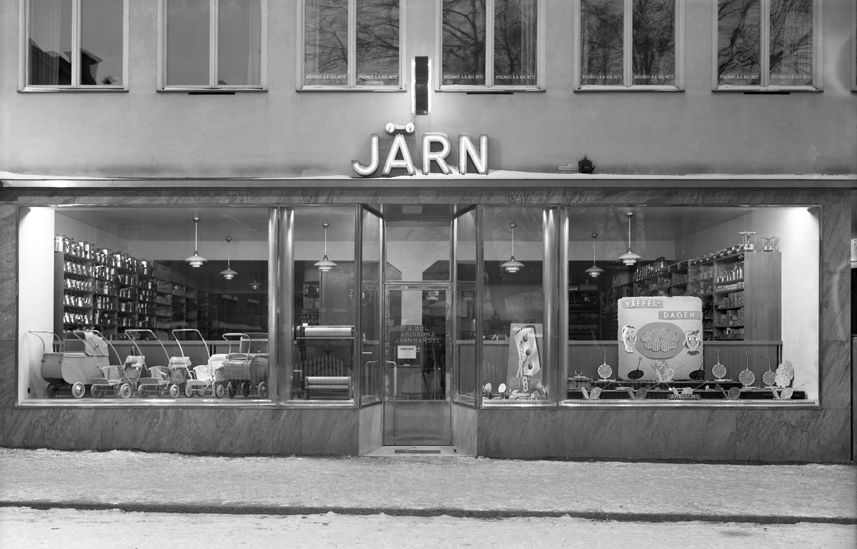 Ahlssons järnhandel i Linköping 1940, vilket motsvarade tiden för öppnadet av firmans nya butik på adressen Sankt Larsgatan 32. Upplysningsvis hade bröderna Wilhelm och Sven Ahlsson haft sin järnhandel inrymd även i adressens föregående hus som rivits och givit plats för det nya. Bilden är daterad den 8 mars, en månad som innebar både många födslar såväl som våffel-dagen, av vilka utan annat sammanträffande lyftes i skylten.