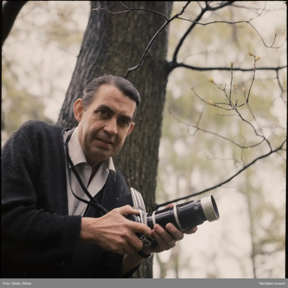 Författaren Rolf Blomberg porträtterad utomhus med kamera i händerna.